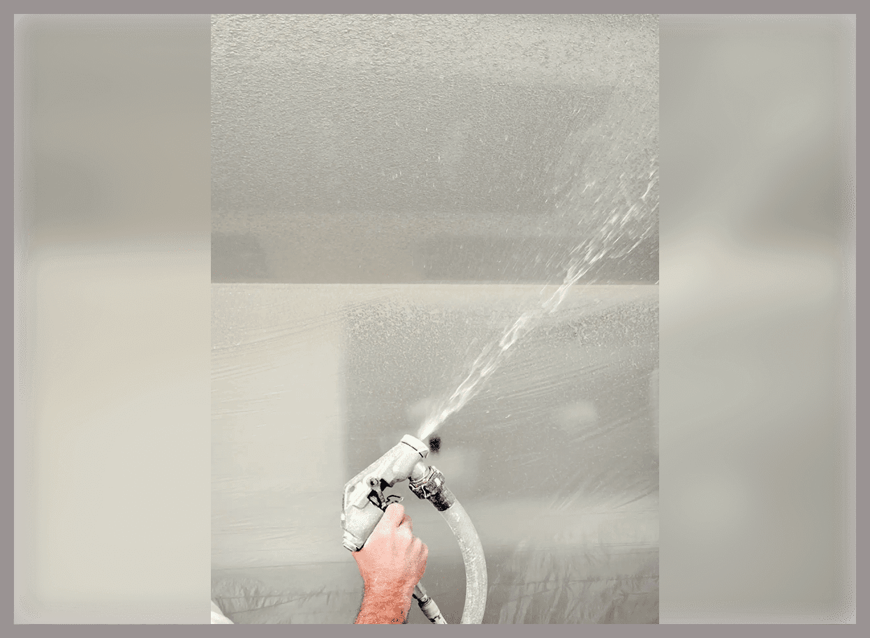 Hand spraying water on a surface.