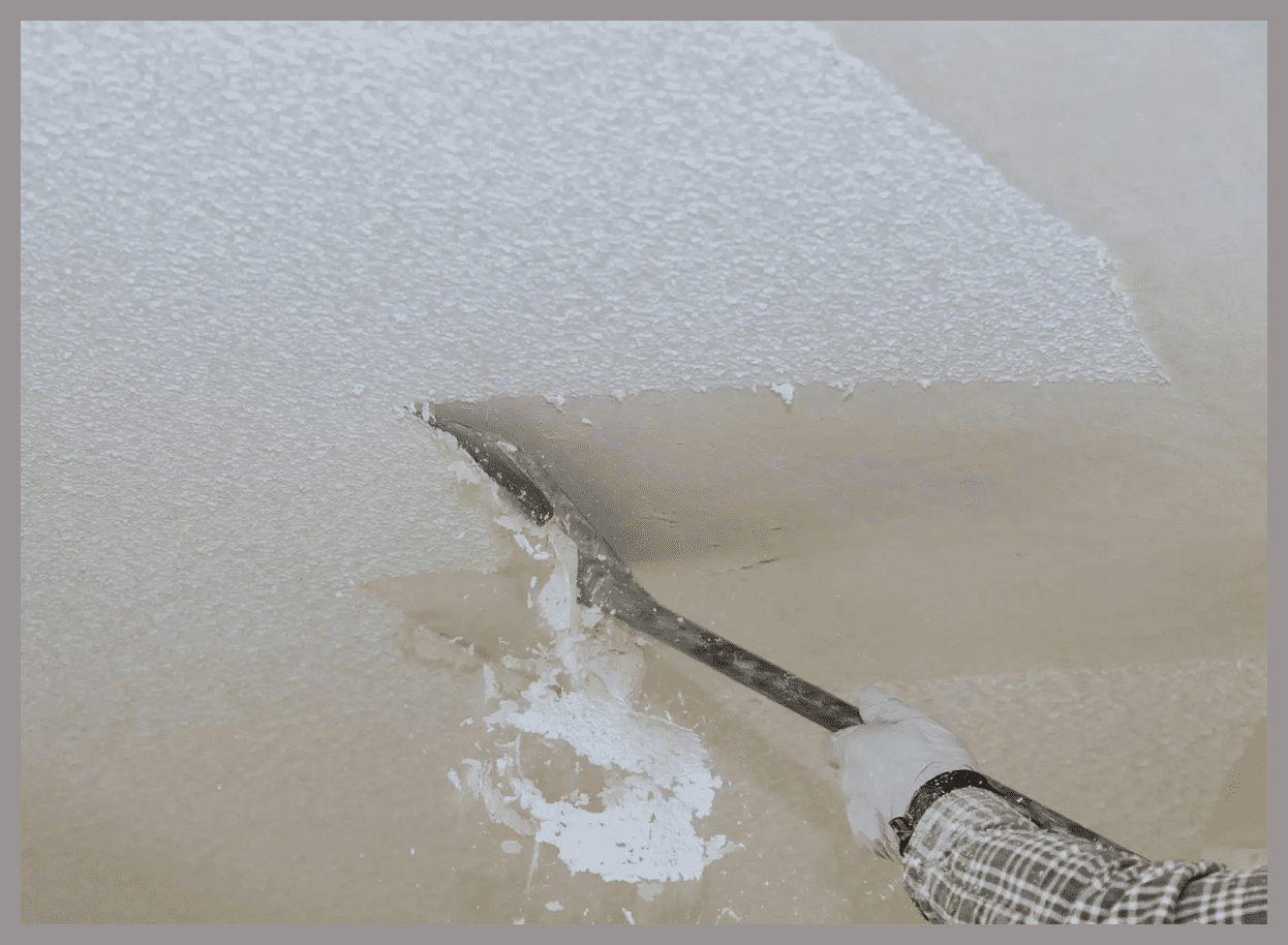 Removing popcorn ceiling with scraper tool.