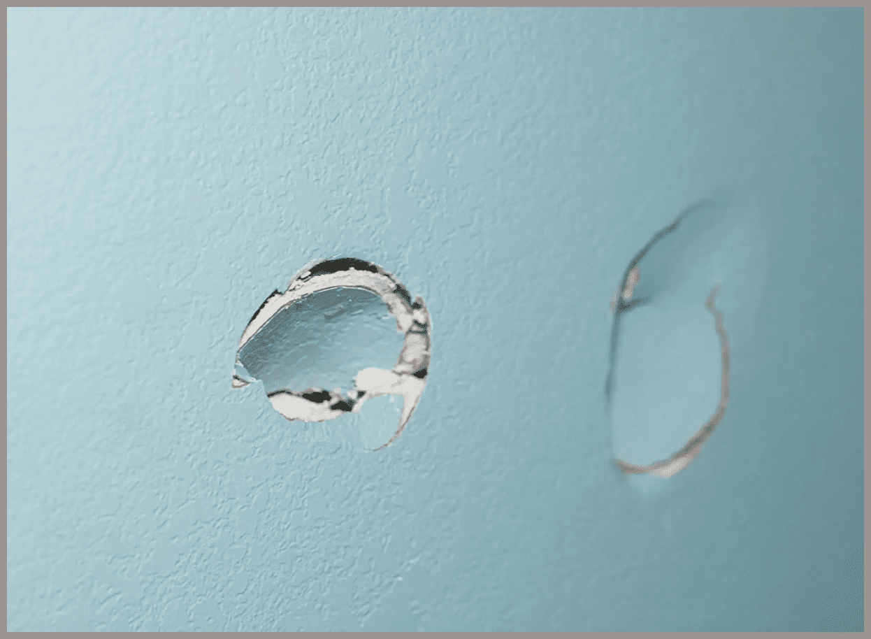 Two holes in a light blue wall.