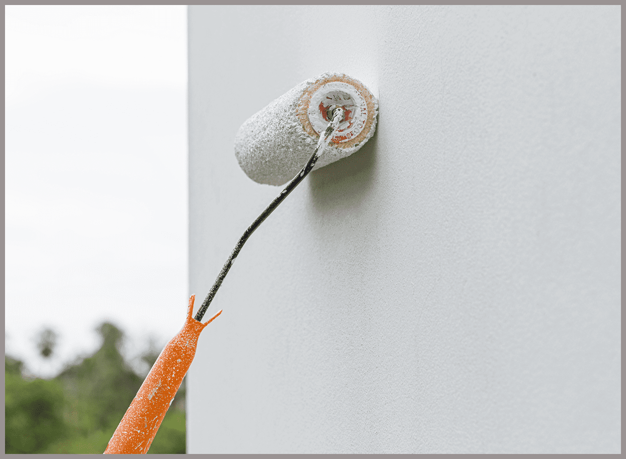 Painting wall with roller on extension pole.