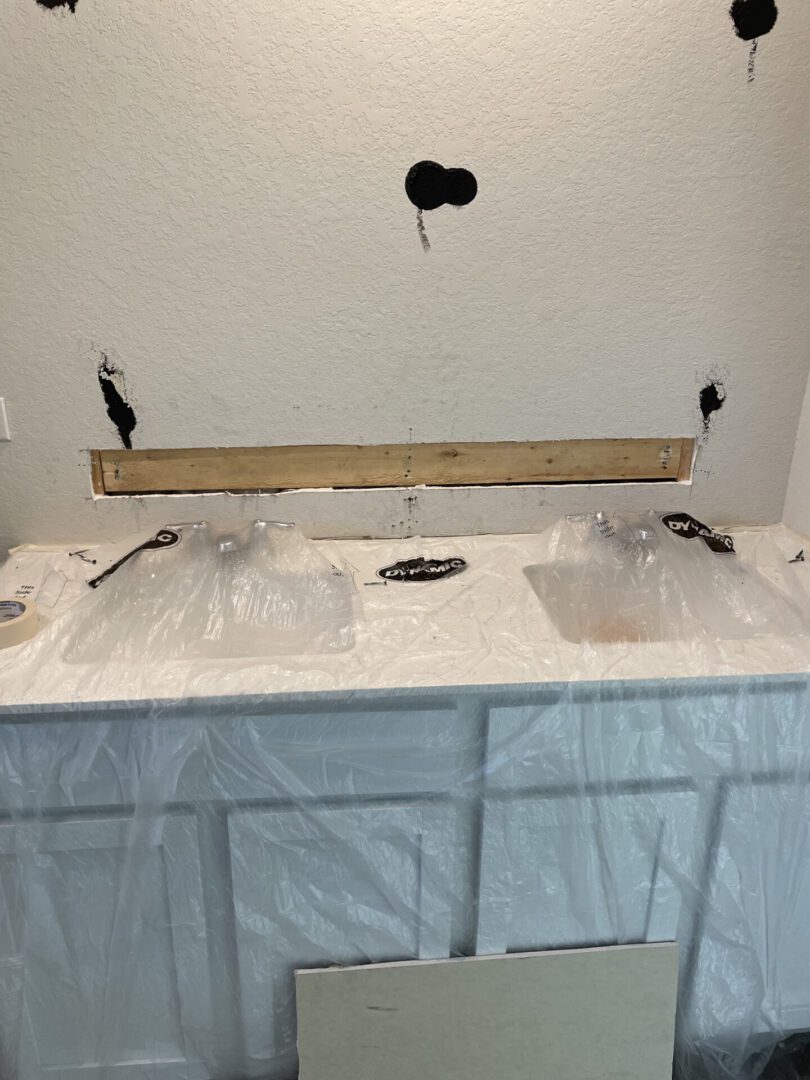 Bathroom renovation with plastic-covered vanity sinks.