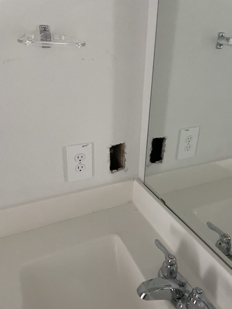 Bathroom sink with wall hole near outlet.