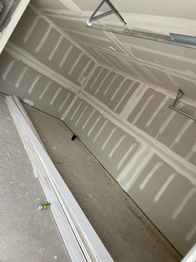 Unfinished garage interior with drywall and planks.
