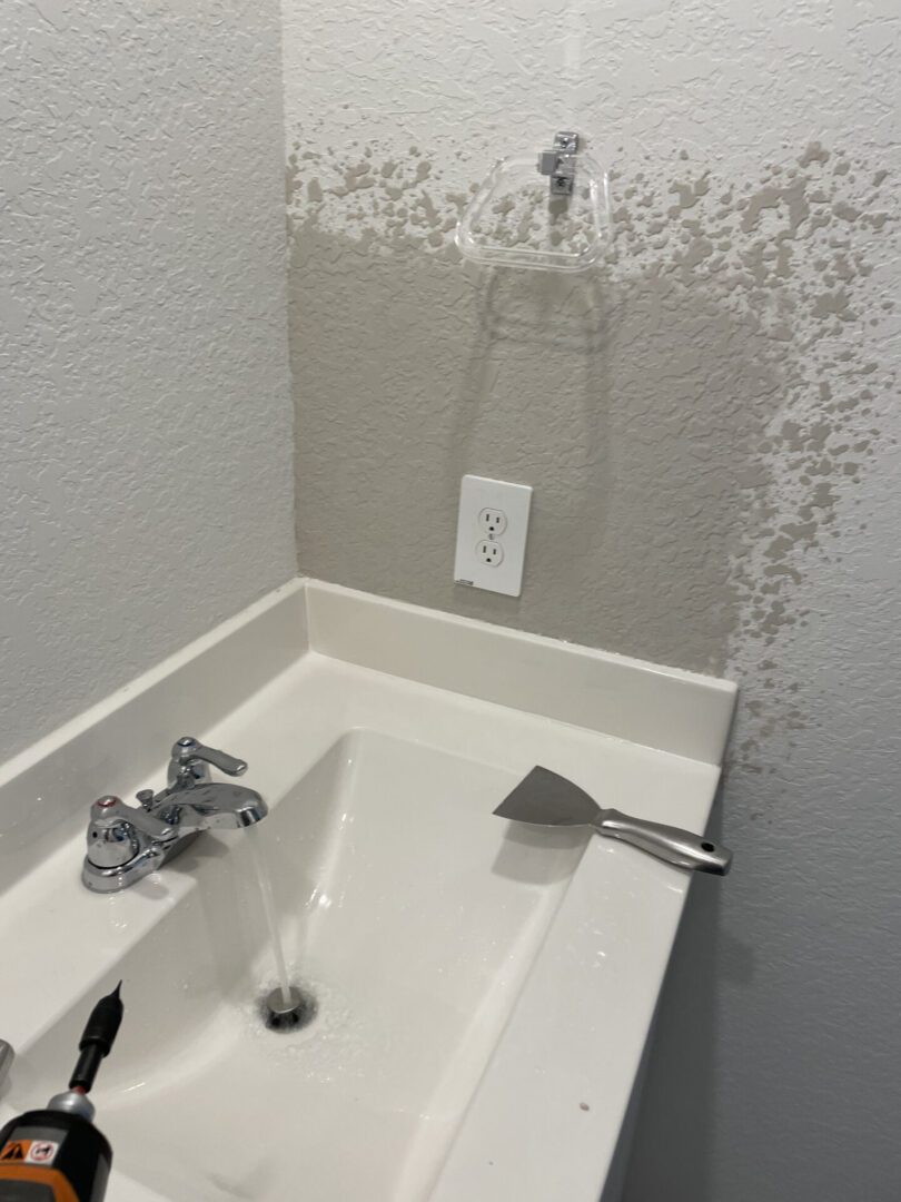 Sink with running water and wall damage.