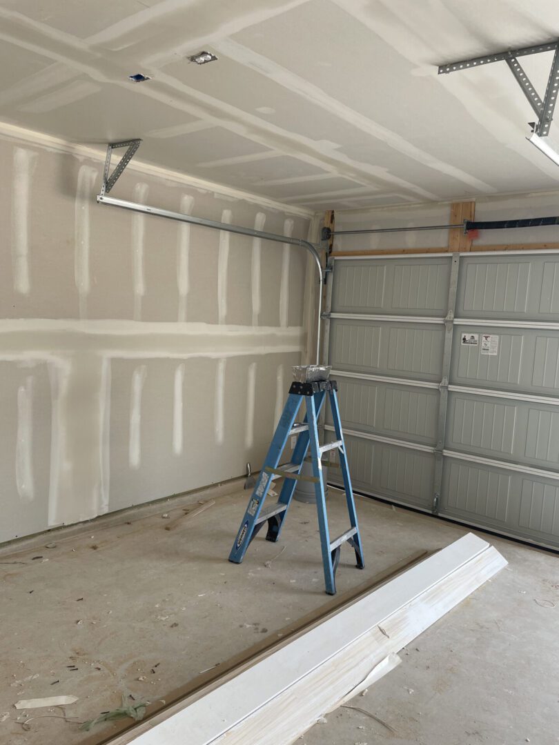 Garage interior with ladder and unfinished walls.