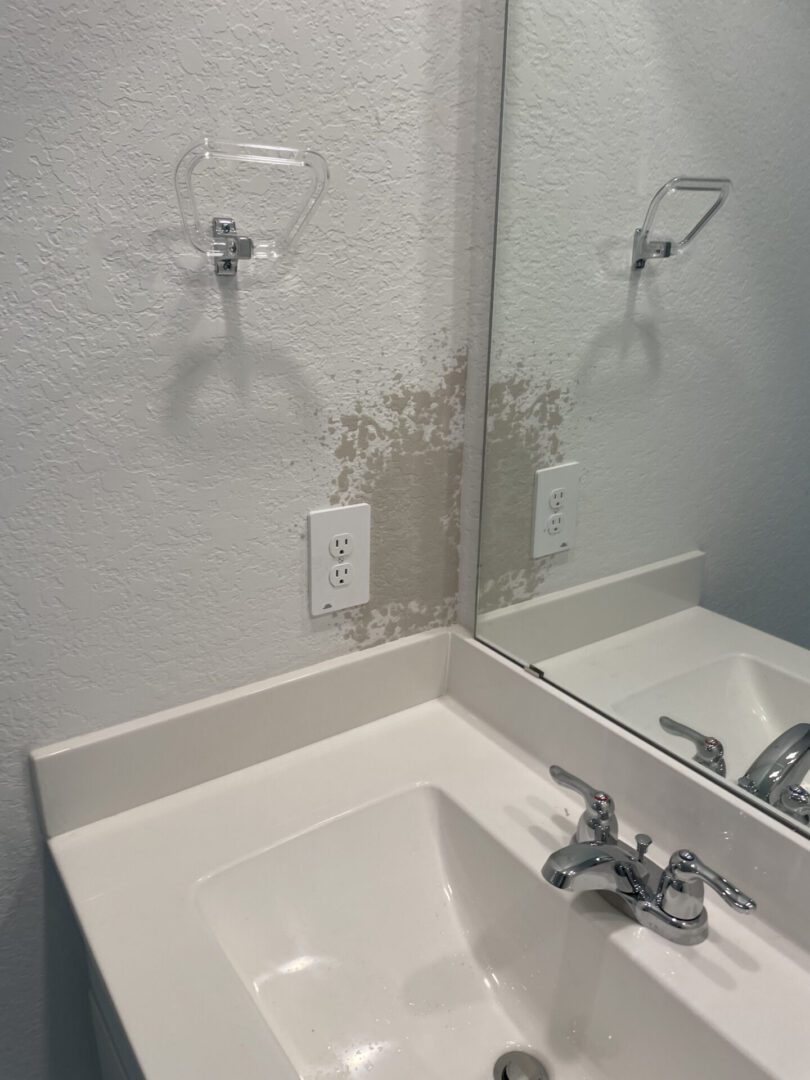 Bathroom sink with wall damage and outlet.