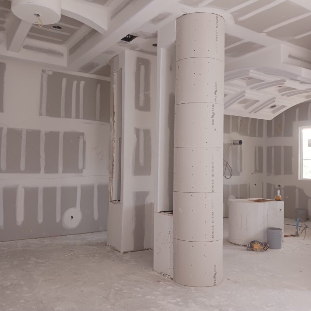 Unfinished room with drywall and column installation.