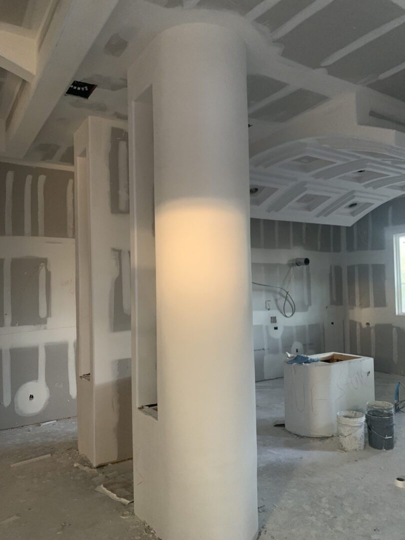 Under construction room with drywall and columns.