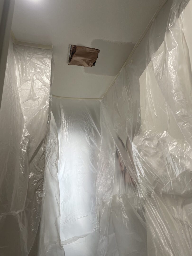Plastic sheets covering walls and ceiling hole.