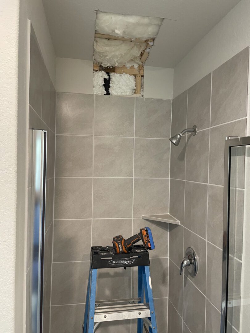 Bathroom ceiling repair with ladder and tools.