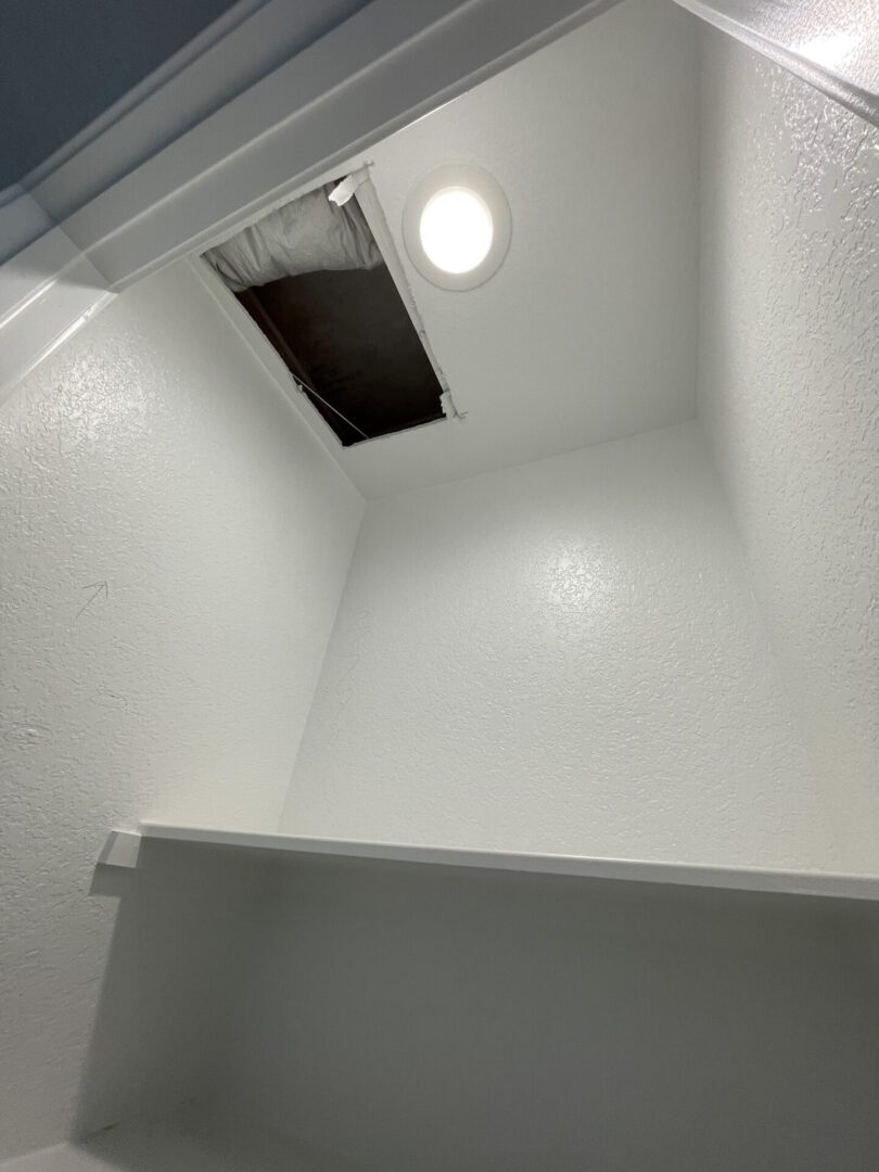 White closet with ceiling access panel.
