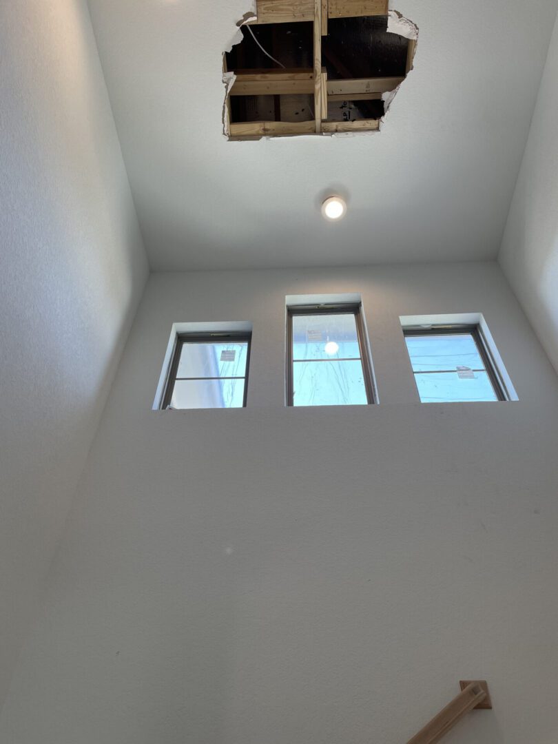Ceiling with hole and three windows visible.