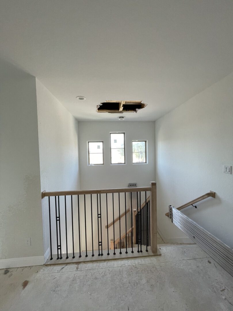 Unfinished hallway with ceiling hole and windows.
