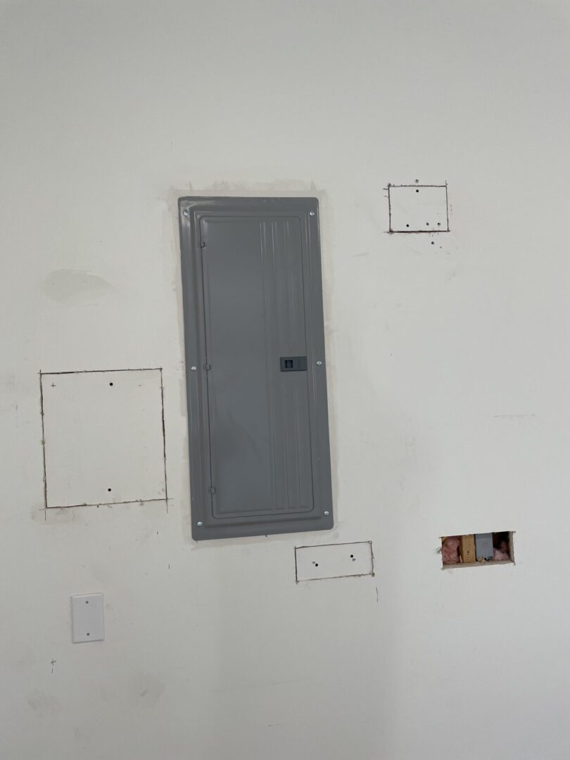Electrical panel and cutouts on white wall.