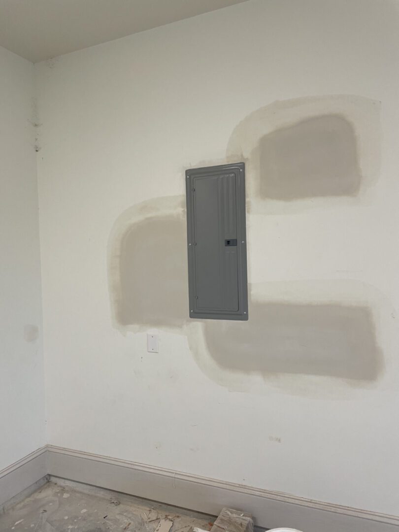 Wall with electrical panel and patched paint.