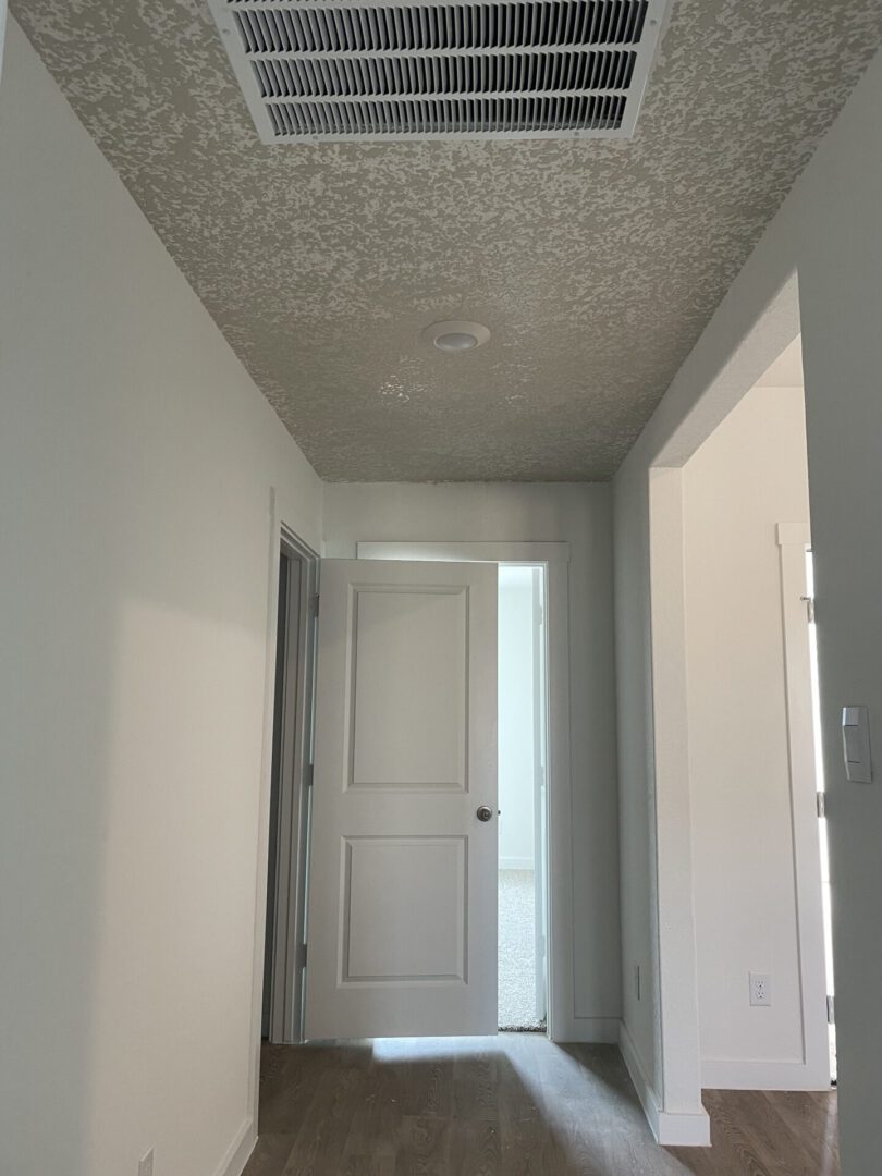 Empty hallway with open white door.