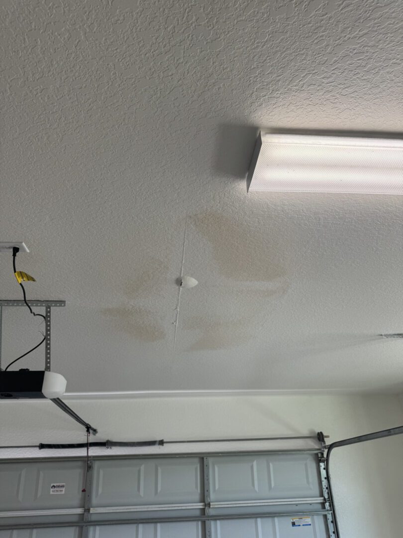 Ceiling water stain in garage with light.