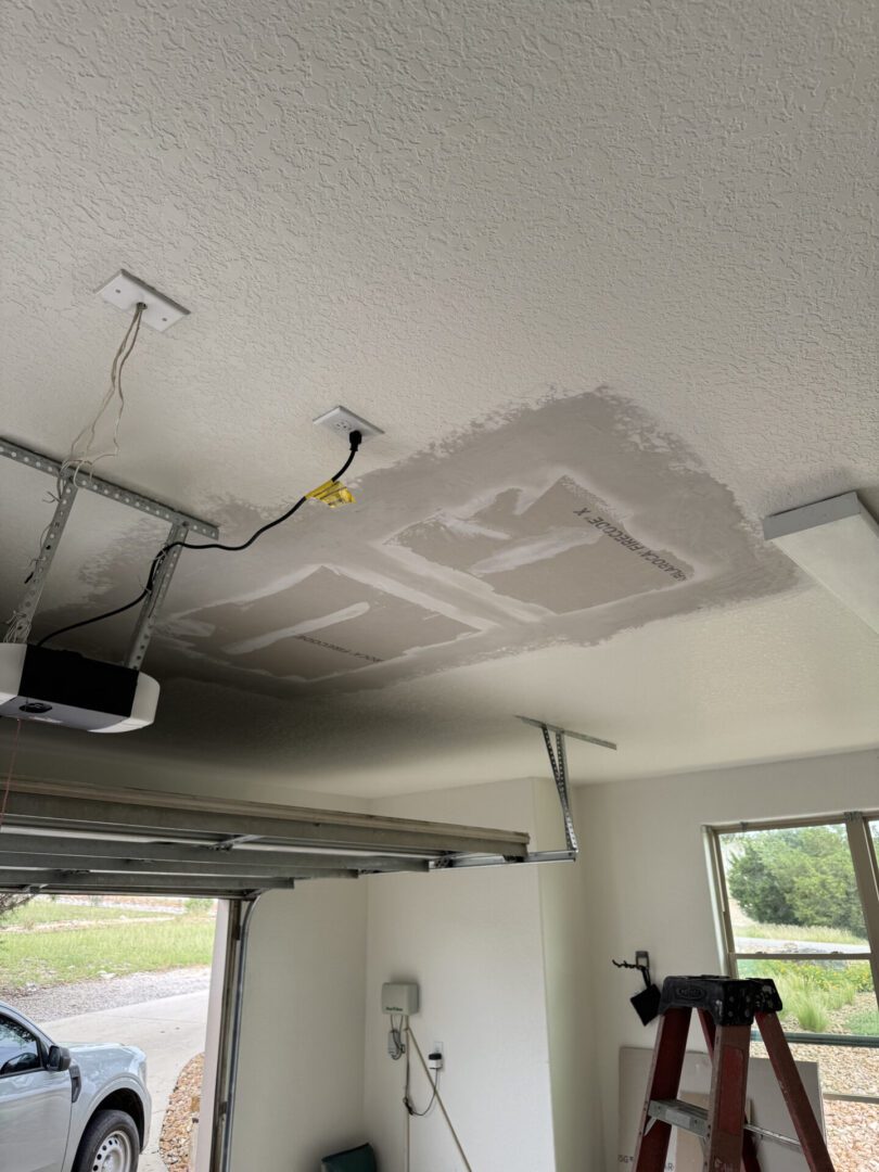 Garage ceiling repair with exposed wiring visible.