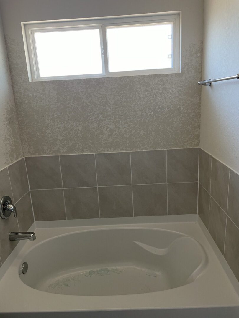 Bathroom with bathtub and window above.