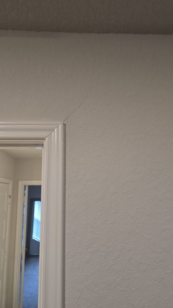 Crack above door frame on wall.