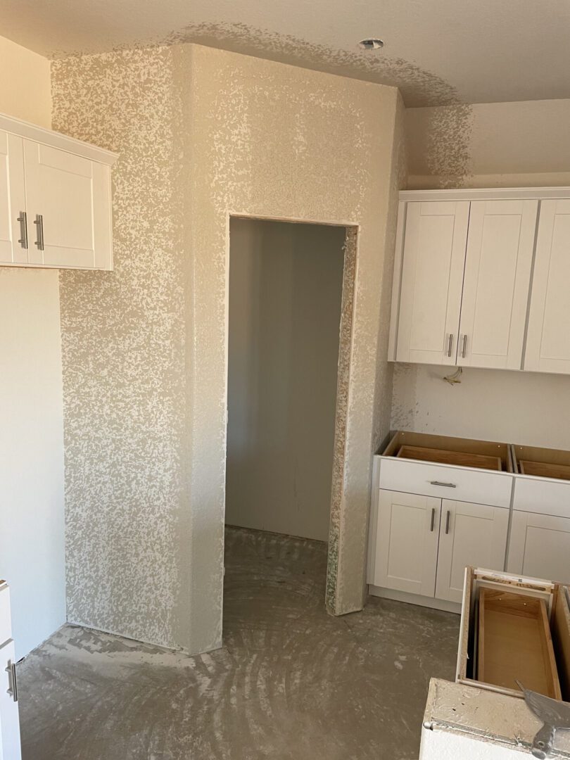 Unfinished kitchen with white cabinets installed.