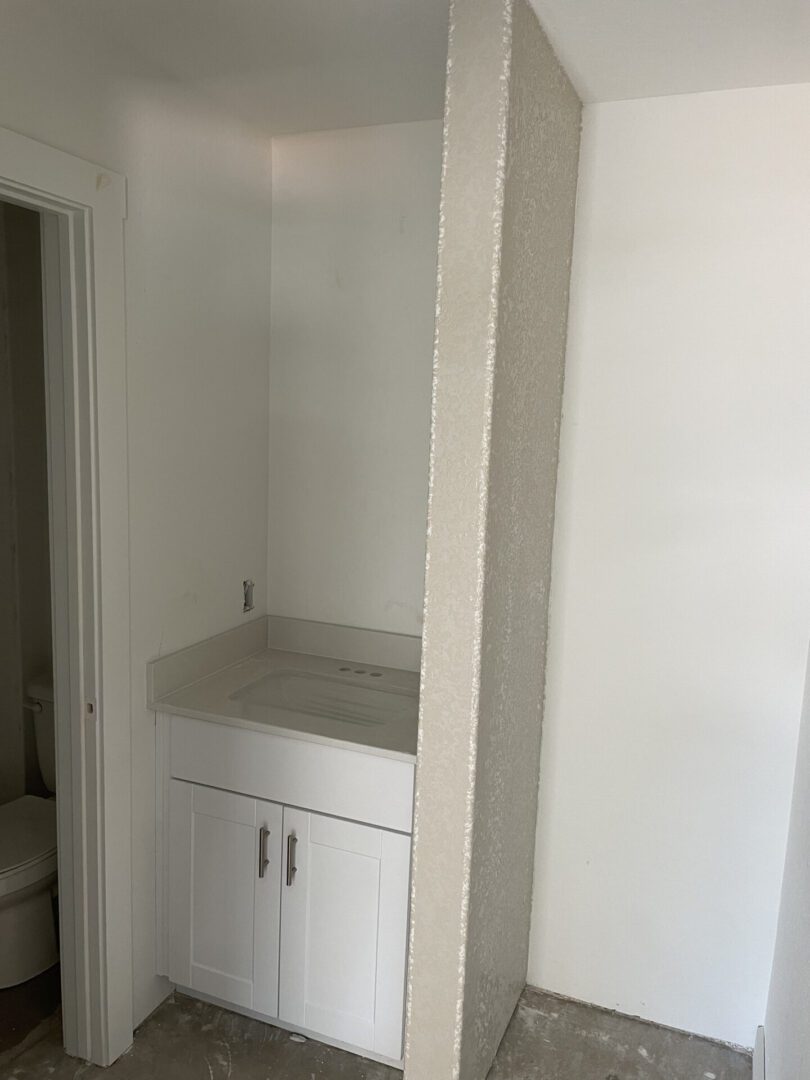 Small bathroom vanity with partial divider wall.