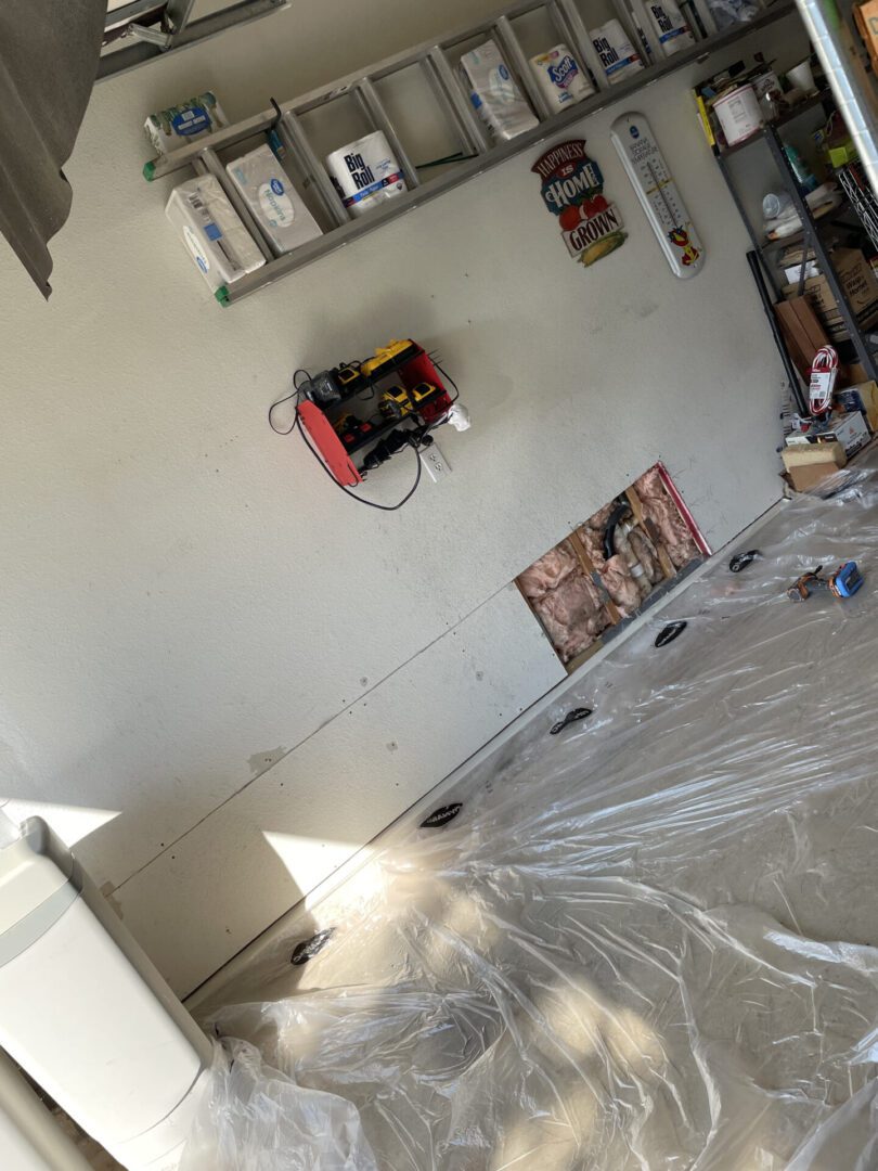 Garage with storage shelves and plastic covering.